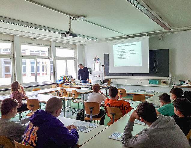 Pas uniquement un aperçu du travail pratique : Cyrill Küng informe une classe sur les possibilités de formation et de formation continue dans les métiers de la construction métallique. Source : zVg